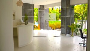 A reception area with a modern design, featuring a reception desk, a large glass window, and a view of greenery outside.