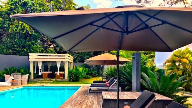 A poolside area with lounge chairs and umbrellas, a wooden deck, and a small gazebo.