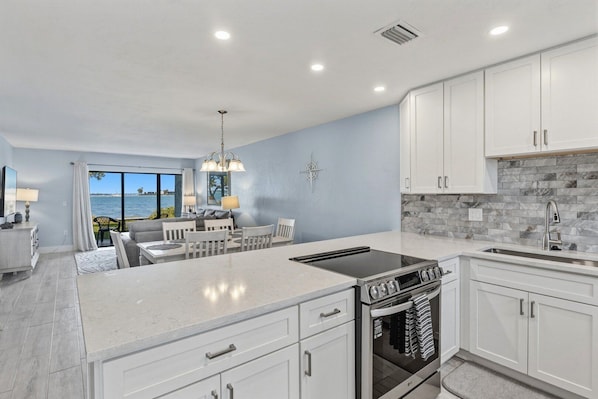 A modern kitchen with white cabinets, a built-in oven, and a large island.