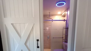 A bathroom with a shower, toilet, and a purple-hued ceiling light fixture. - Nelly house (Oxford)