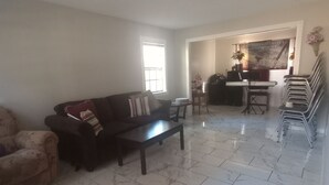 A living room with a sofa, a coffee table, and a dining area with chairs and a table. - Nelly house (Oxford)