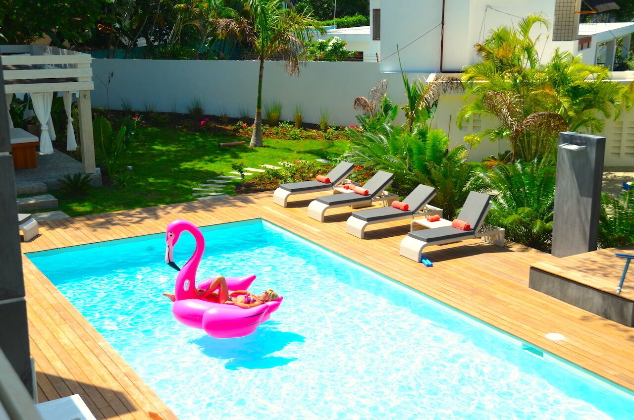 Una piscina con sillas de descanso y un flotador con forma de flamenco rosa.