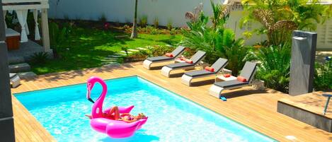 Una piscina con sillas de descanso y un flotador con forma de flamenco rosa.