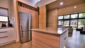 Una cucina moderna con frigorifero in acciaio inossidabile, mobili in legno e una parete in pietra.