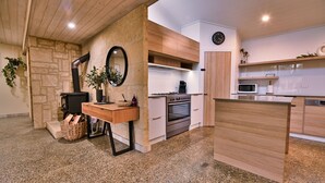 Una cucina moderna con parete in pietra, pensili in legno, forno integrato e microonde.
