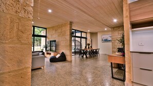 Un'ampia zona giorno con parete in pietra, soffitto in legno e una grande finestra.