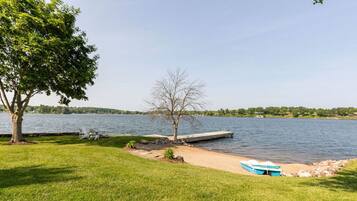 Une propriété au bord du lac, dotée d’un quai, d’un bateau et d’une zone herbeuse avec un arbre.