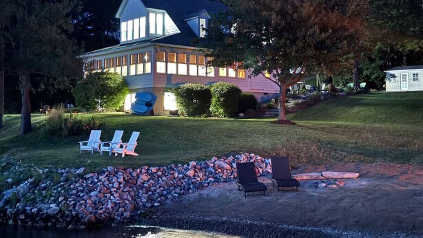 Ein großzügiges Haus mit gepflegtem Rasen, Sitzgelegenheit im Freien und einem Schwimmbad.