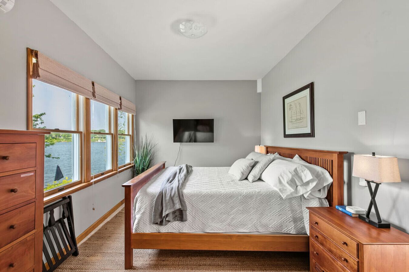 Une chambre à coucher avec un lit, une commode en bois et un téléviseur fixé au mur.