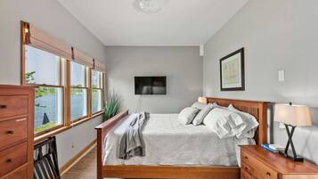 Une chambre à coucher avec un lit, une commode en bois et un téléviseur fixé au mur.