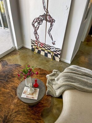 Relax in a stylish space with a plush rug, a cozy seating area, and a vibrant abstract painting.