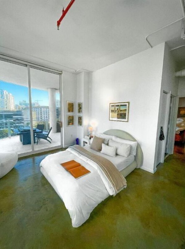 Enjoy a city view from the comfort of this stylish room, featuring a large bed and a seating area with a table and chairs.