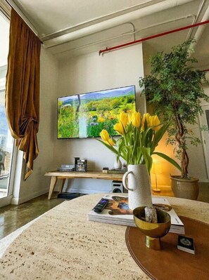 Relax in a serene space with a large flat-screen TV, a round table, and a potted plant.