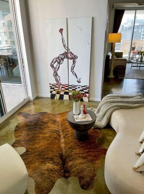 Relax in this stylish living room with a comfortable armchair and sofa, a coffee table, and a beautiful city view.