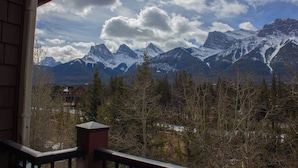 Blick auf Berge vom Balkon, mit schneebedeckten Gipfeln und blauem Himmel.
