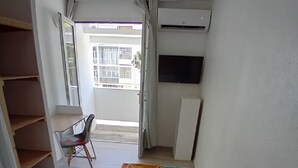 Ein schmaler Flur mit einem gemusterten Teppich, einem Sessel und einem großen Fenster.