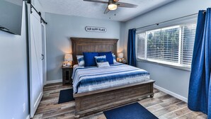 A bedroom with a bed, a ceiling fan, a window with curtains, and a sign on the wall. - Waterfront Sleeps 6 w/private boat dock and heated pool. (Crystal River)