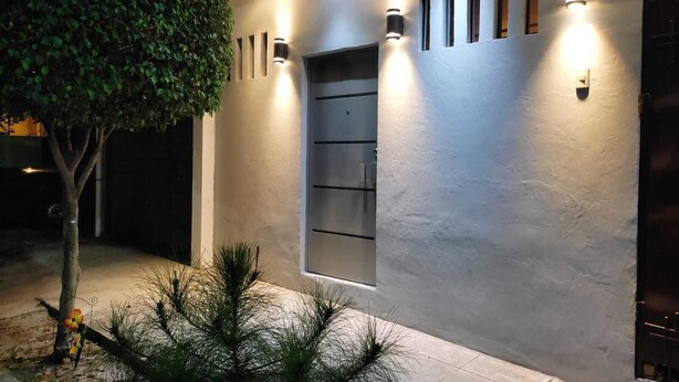 Un bâtiment moderne à la façade épurée, doté d’un éclairage encastré et d’une petite fenêtre.