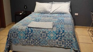 Une chambre à coucher comprenant un lit, une table de chevet, un climatiseur et une chaise.