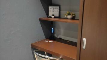 A small room with a desk, a chair, and a shelf with a sign that reads "Hogar Dulce Hogar".