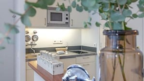 A kitchen with a microwave, a sink, and a countertop with glassware. - Modern apartment with balcony, in direct beach location - Andreas-Dirks-Straße 5 (Sylt)