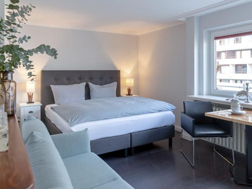 A modern bedroom with a bed, bedside tables, a desk, and a chair.