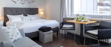 Habitación de hotel moderna con cama, escritorio, silla y vistas a la ciudad.
