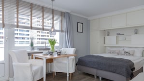 A modern bedroom with a bed, a desk, and chairs. - Modern apartment with balcony, in direct beach location - Andreas-Dirks-Straße 5 (Sylt)