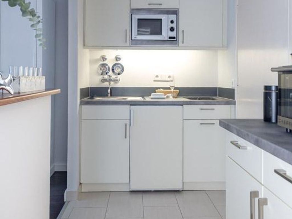 A modern kitchen with white cabinetry, a microwave, and a sink.