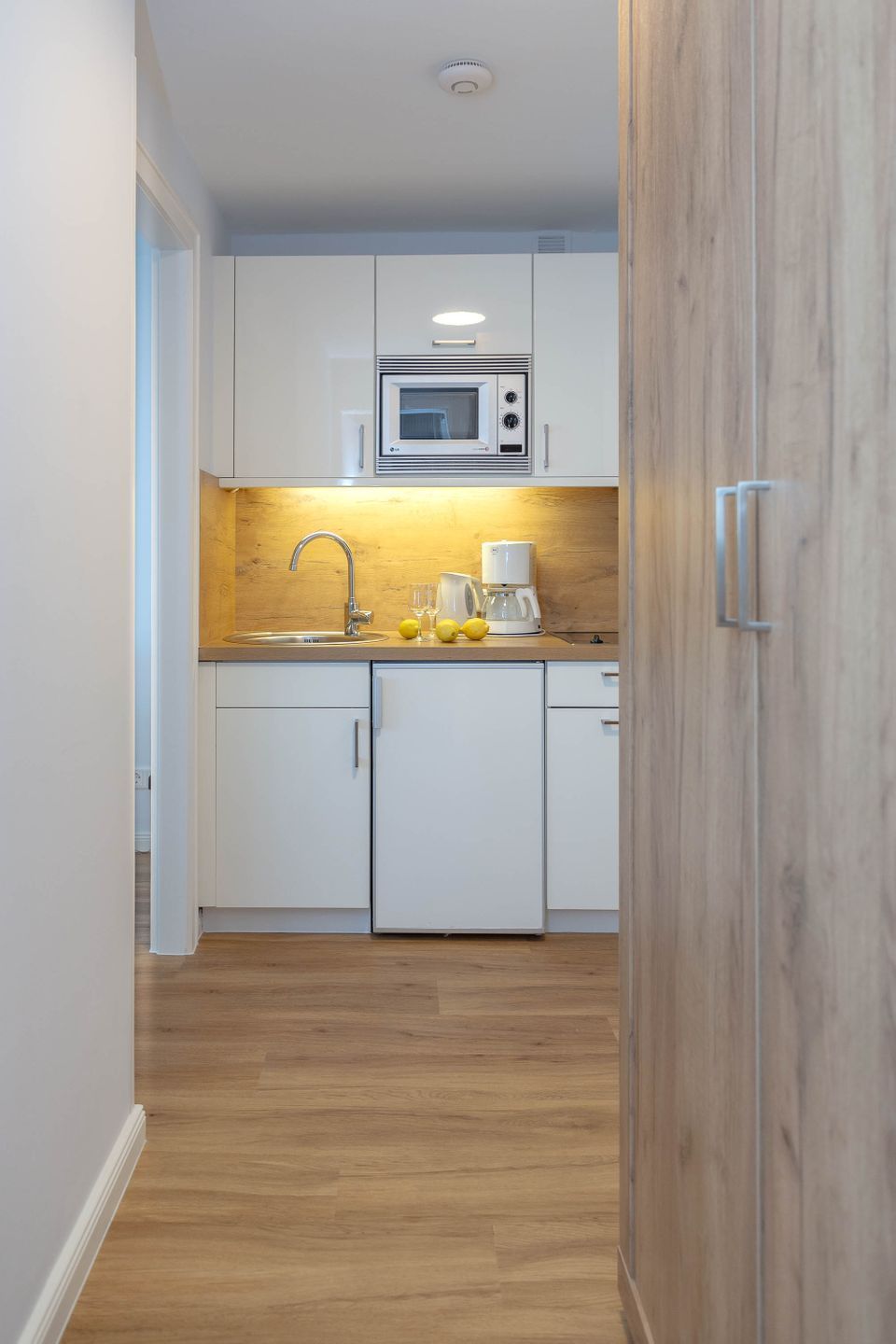 Une cuisine moderne avec des armoires blanches, un comptoir en bois et un four à micro-ondes encastré.