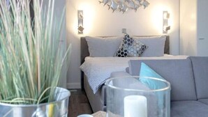 Ein modernes Wohnzimmer mit einem grauen Sofa, einem Couchtisch mit einer Glasvase und einer Topfpflanze.