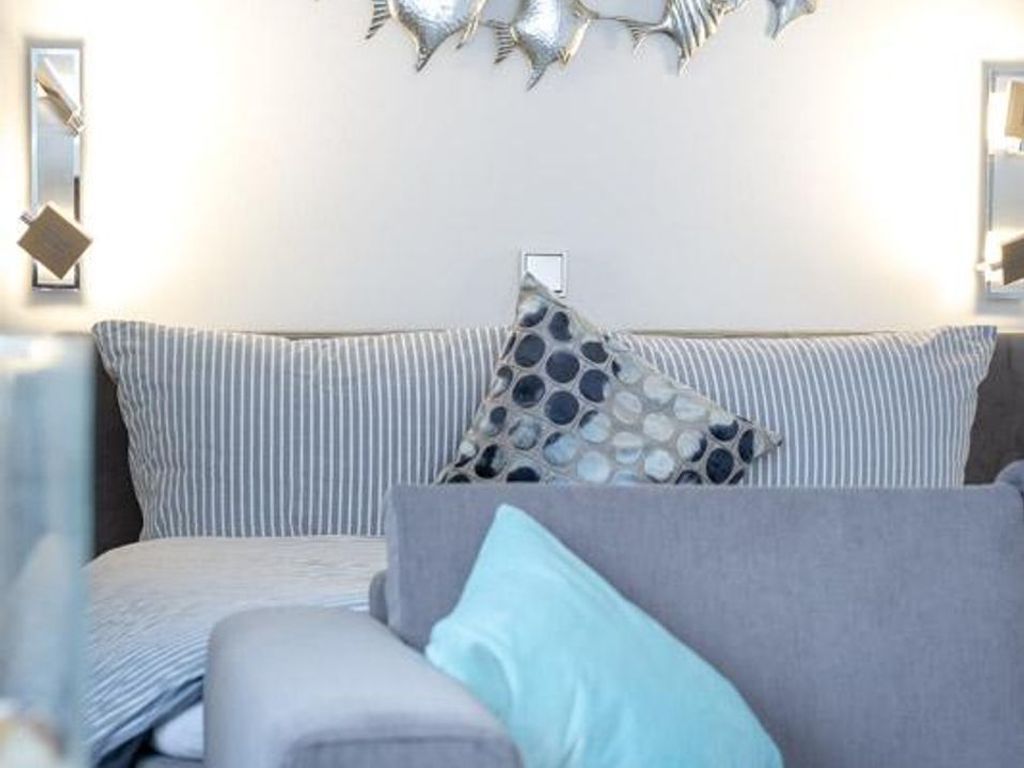 A modern living room with a grey sofa, striped cushions, and a decorative wall piece.