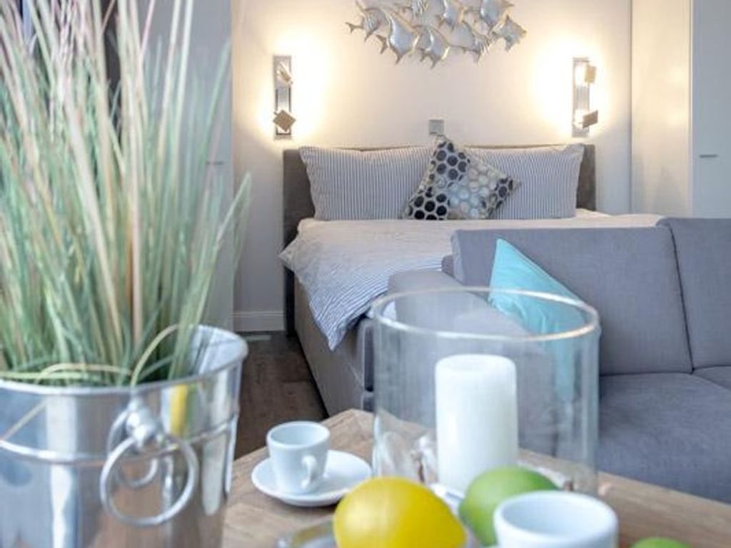 A modern living room with a grey sofa, a coffee table with a glass vase, and a potted plant.