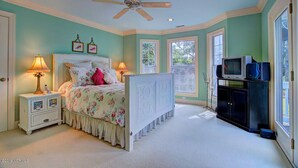 A bedroom with a bed, nightstands, a ceiling fan, and a TV stand. - Ingen Trafikk secluded forest oasis (Bald Head Island)