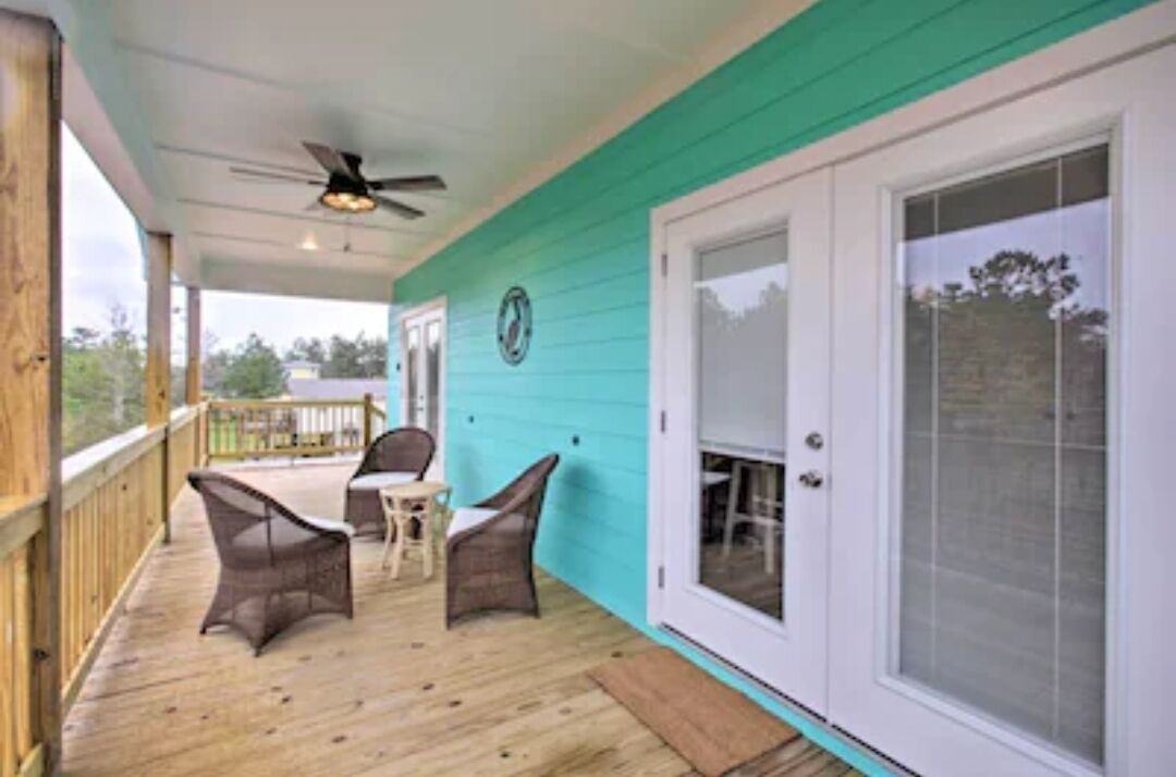 A covered porch with wicker furniture and a ceiling fan.