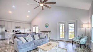 A spacious living area with a gray sofa, a wooden coffee table, and a patterned armchair. - Bay St Louis Water Front Home w/ Private Pool + Boat Dock (Bay St Louis)