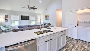A modern kitchen with white cabinetry, a built-in dishwasher, and a large island with a sink. - Bay St Louis Water Front Home w/ Private Pool + Boat Dock (Bay St Louis)