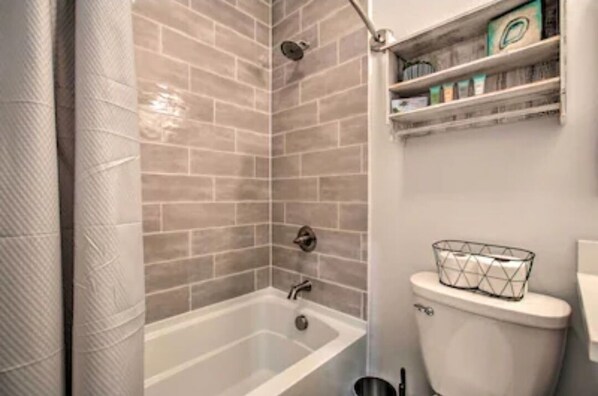 A bathroom with a bathtub, a toilet, and a shower area with tiled walls.