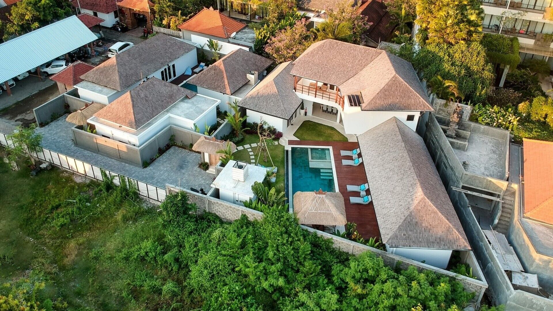 Vista aérea de una zona residencial con varias casas, una piscina y abundante vegetación.