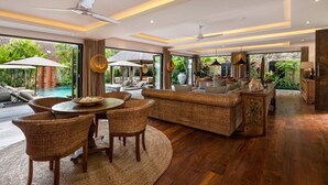A modern living room with a pool view, wicker furniture, and a stone wall. - Modern 4BR Villa W/ Pool & Balcony, Bali Villa 2220 (Bali)