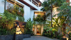 A modern building with a large statue in the foreground, surrounded by lush tropical plants. - Modern 4BR Villa W/ Pool & Balcony, Bali Villa 2220 (Bali)