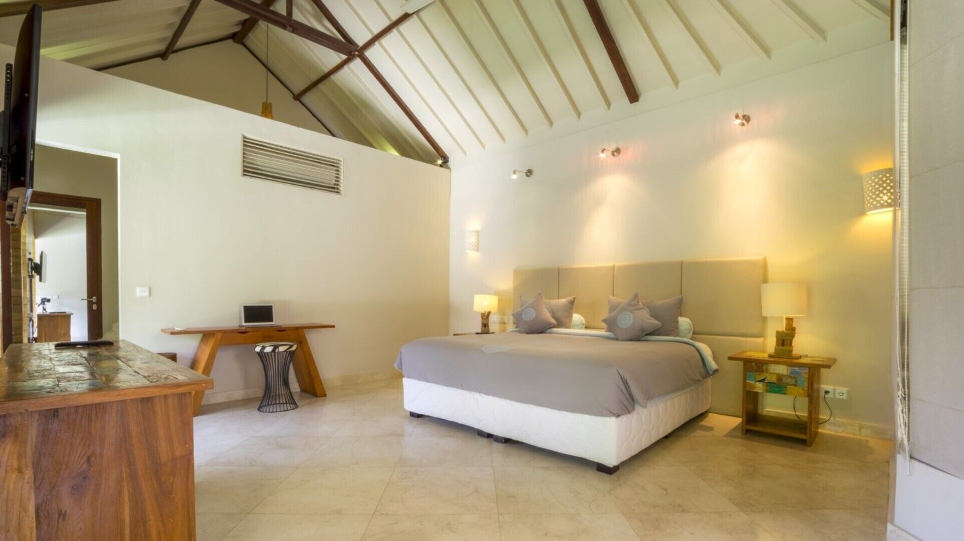 A bedroom with a bed, bedside tables, a desk, and a chair.