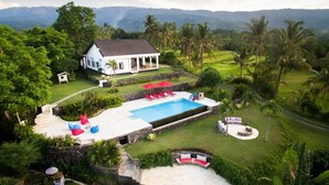 Una casa amb piscina, envoltada de vegetació abundant i palmeres.