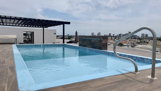 A rooftop swimming pool with a clear view of the city skyline. - Departamento con alberca en El Encanto (Mazatlán)