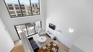 Eine moderne Wohnung mit Essbereich, Wohnzimmer mit Sofa und Fernseher sowie ein Balkon mit Blick auf andere Gebäude.