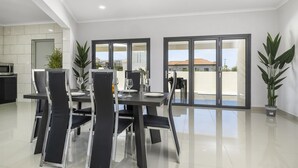 A modern dining area with a black table and chairs, a microwave, and potted plants. - *NEW* 4BR4BA Villa across of PalmBeach w/ Pvt Pool (Noord)