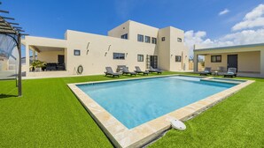 A modern two-story house with a swimming pool, outdoor seating, and a well-maintained lawn. - *NEW* 4BR4BA Villa across of PalmBeach w/ Pvt Pool (Noord)