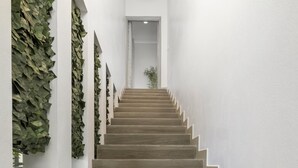 A wooden staircase with white walls and a circular light fixture at the top. - *NEW* 4BR4BA Villa across of PalmBeach w/ Pvt Pool (Noord)