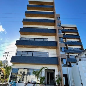 Un edificio de varios pisos con un diseño arquitectónico moderno, que combina fachadas de ladrillo y vidrio y un techo plano.