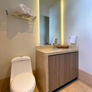 Un baño moderno con inodoro, tocador con espejo y toallero.
